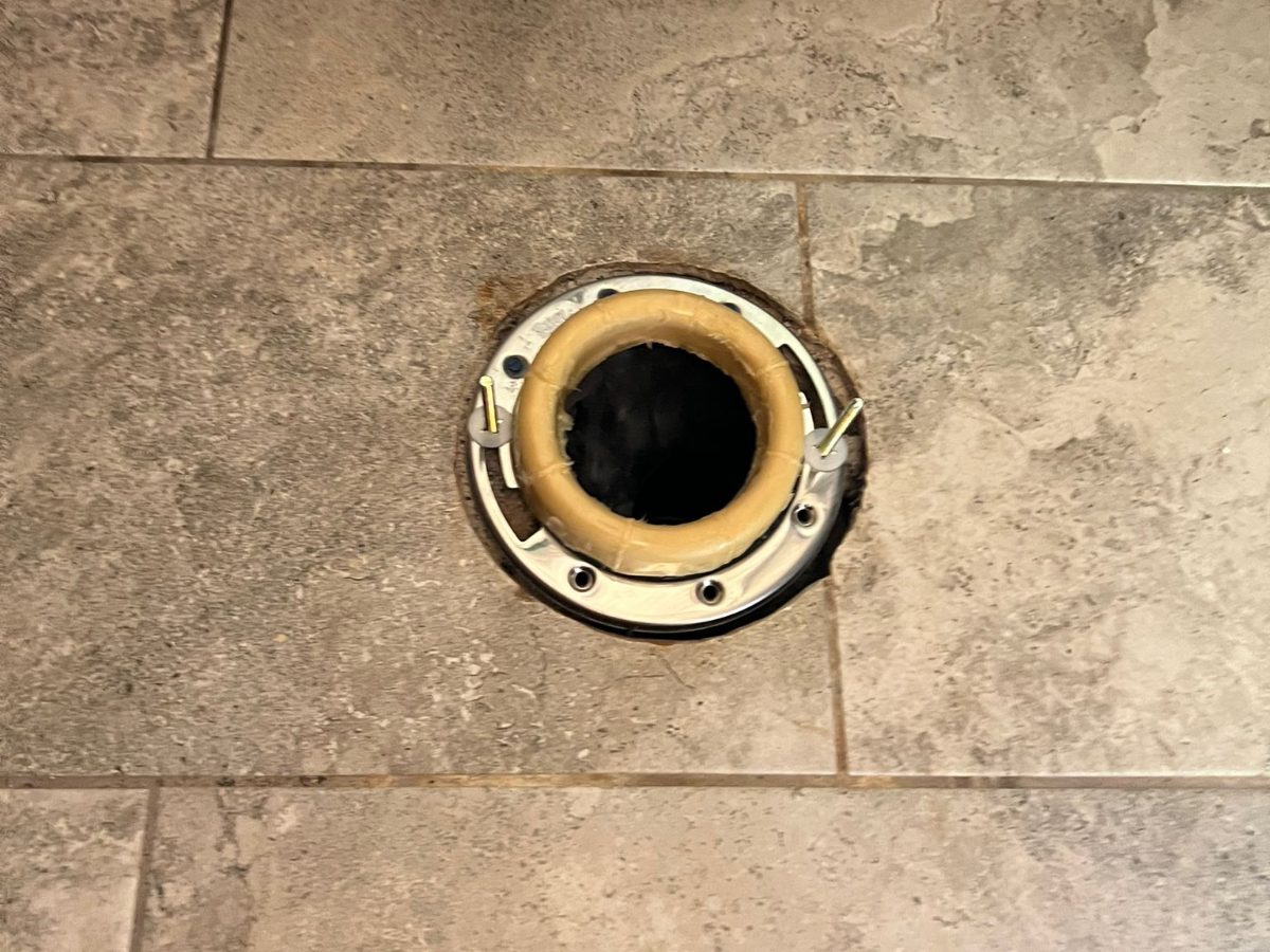 Shower drain opened up on a tile floor for cleaning
